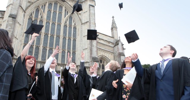 Graduates throw caps in the air outside Winchester Cathedral