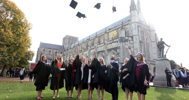 Graduates throw caps in the air outside Winchester Cathedral