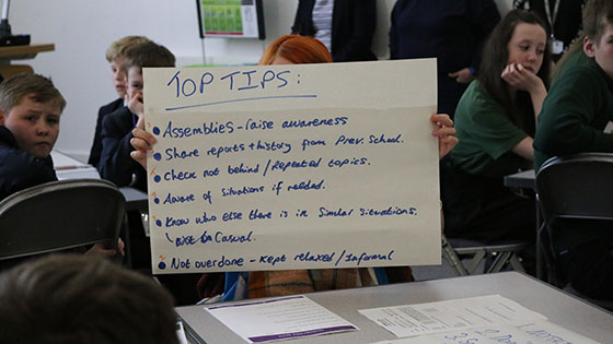 School child holds sign reading 'top tips', listing tips for service children