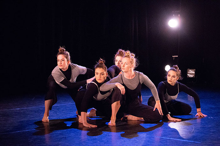 Five female dancers crouching on stage