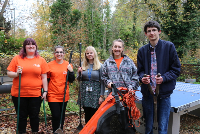 Volunteers in orange tops at Trinity Winchester with gardening tools
