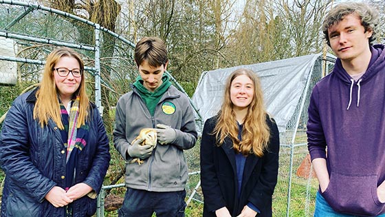 Four students in a group one holding an owl