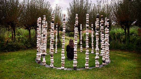 person sitting in circle of stones in the countryside