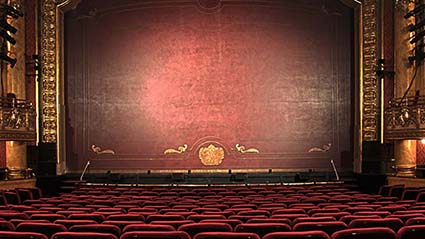 Stage with curtain drawn set behind red seats