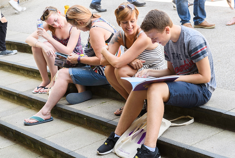 Two students at an open day sat with parents